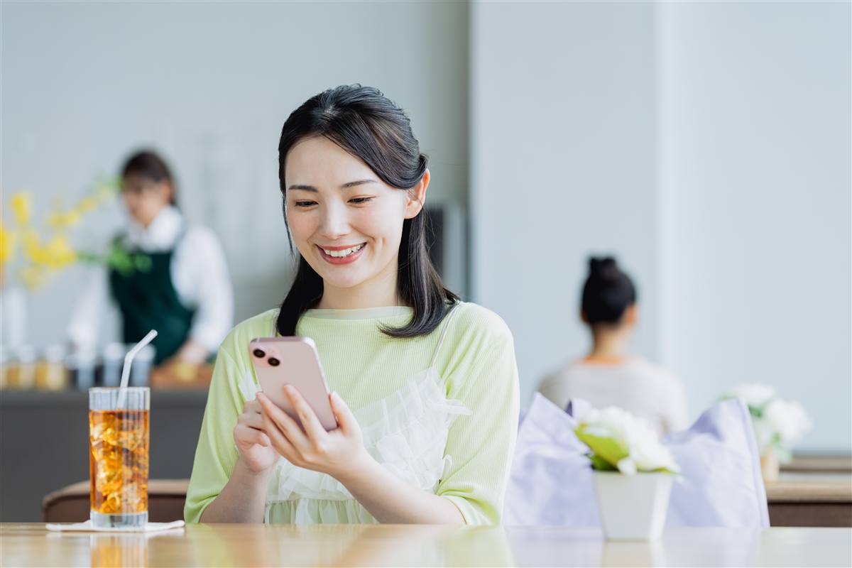 カフェでスマートフォンを見て笑う女性