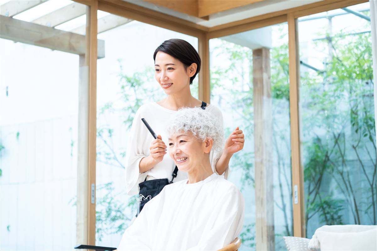 明るい店内で、お客様の髪をとかす美容師