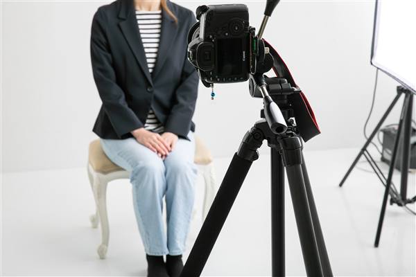 三脚に載せた一眼カメラと、撮影の準備をするフォトグラファー
